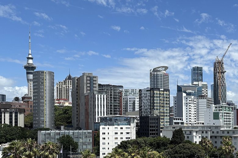 Office towers and the Sky Tower on the Auckland city skyline under a blue sky